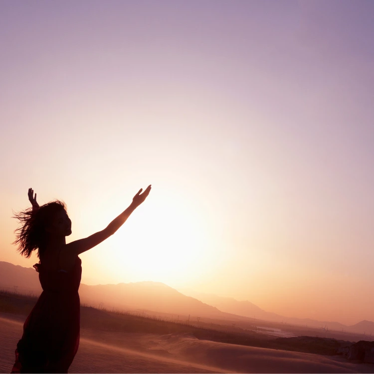 Femme épanouie levant les bras vers le cielface à un lever de soleil
